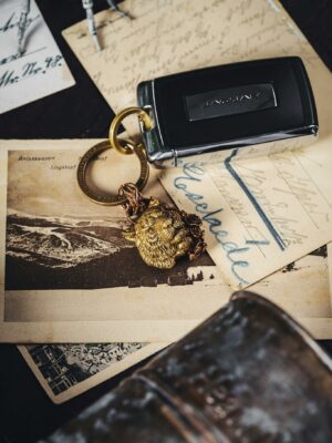 A modern car key resting on vintage postcards with a lion-head keychain.