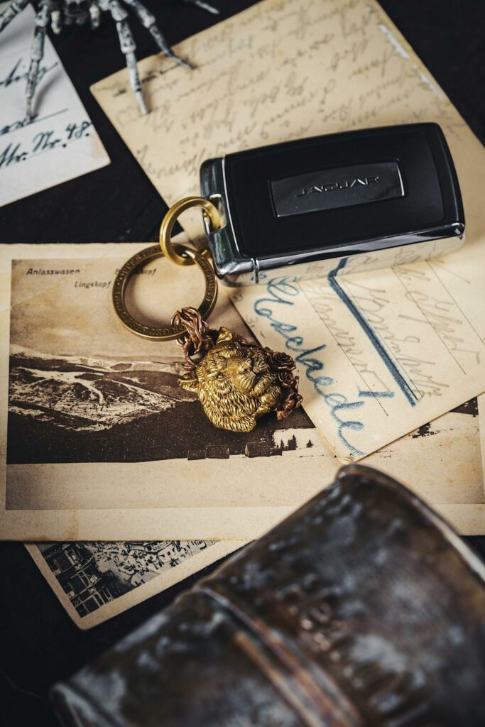 A modern car key resting on vintage postcards with a lion-head keychain.