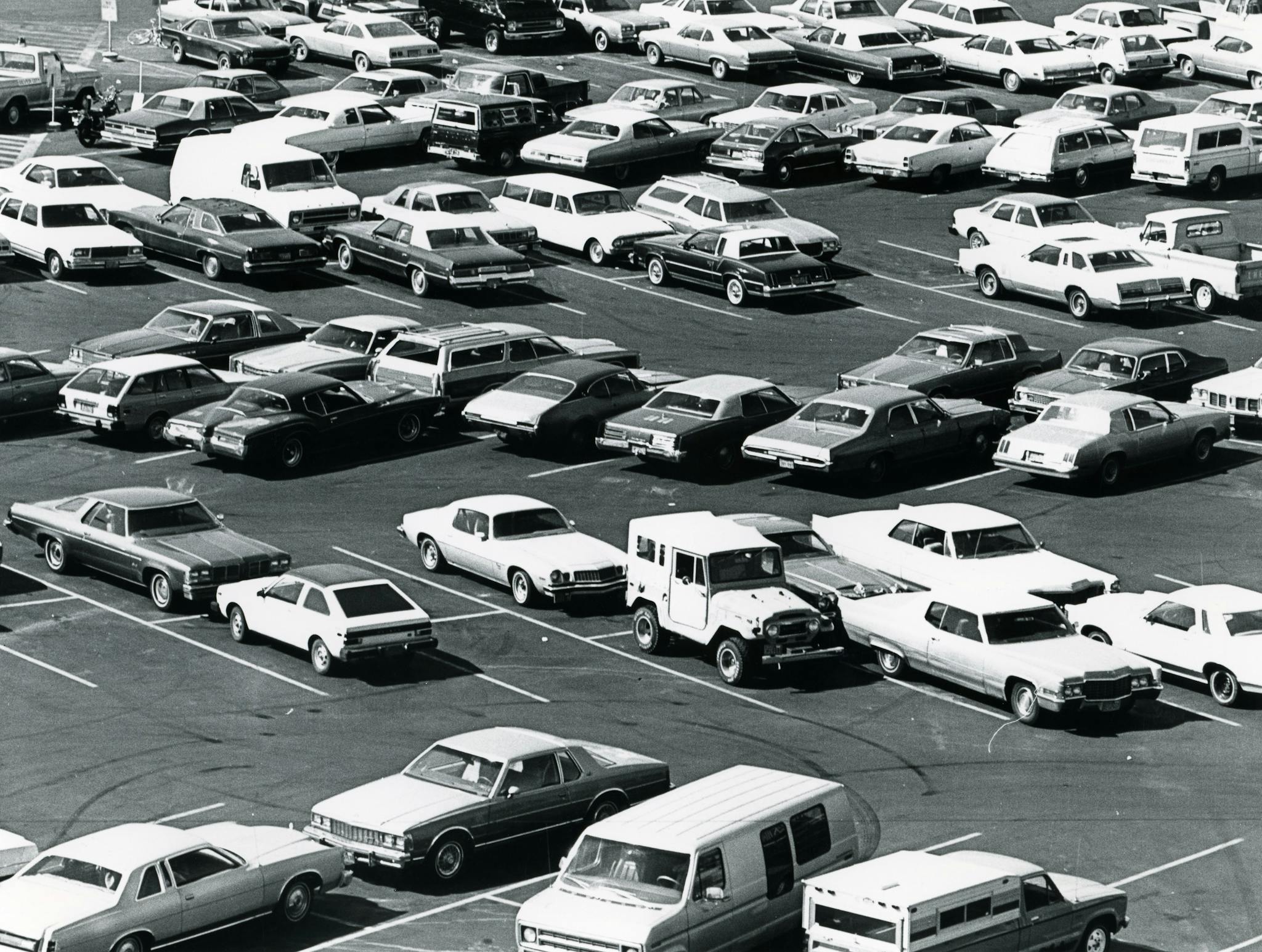 Aerial view of a parking lot filled with vintage cars in a classic black and white setting.