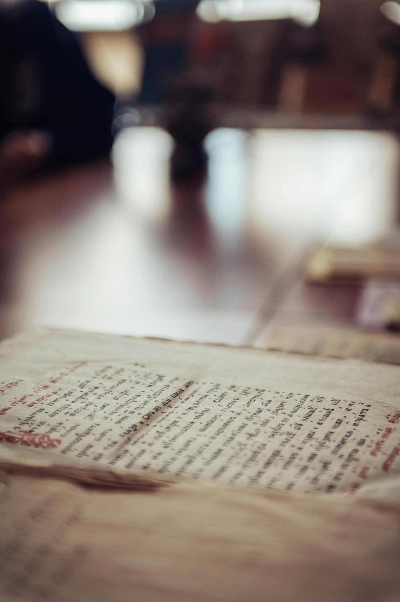 Close-up of an ancient manuscript with handwritten text on a blurred wooden table.