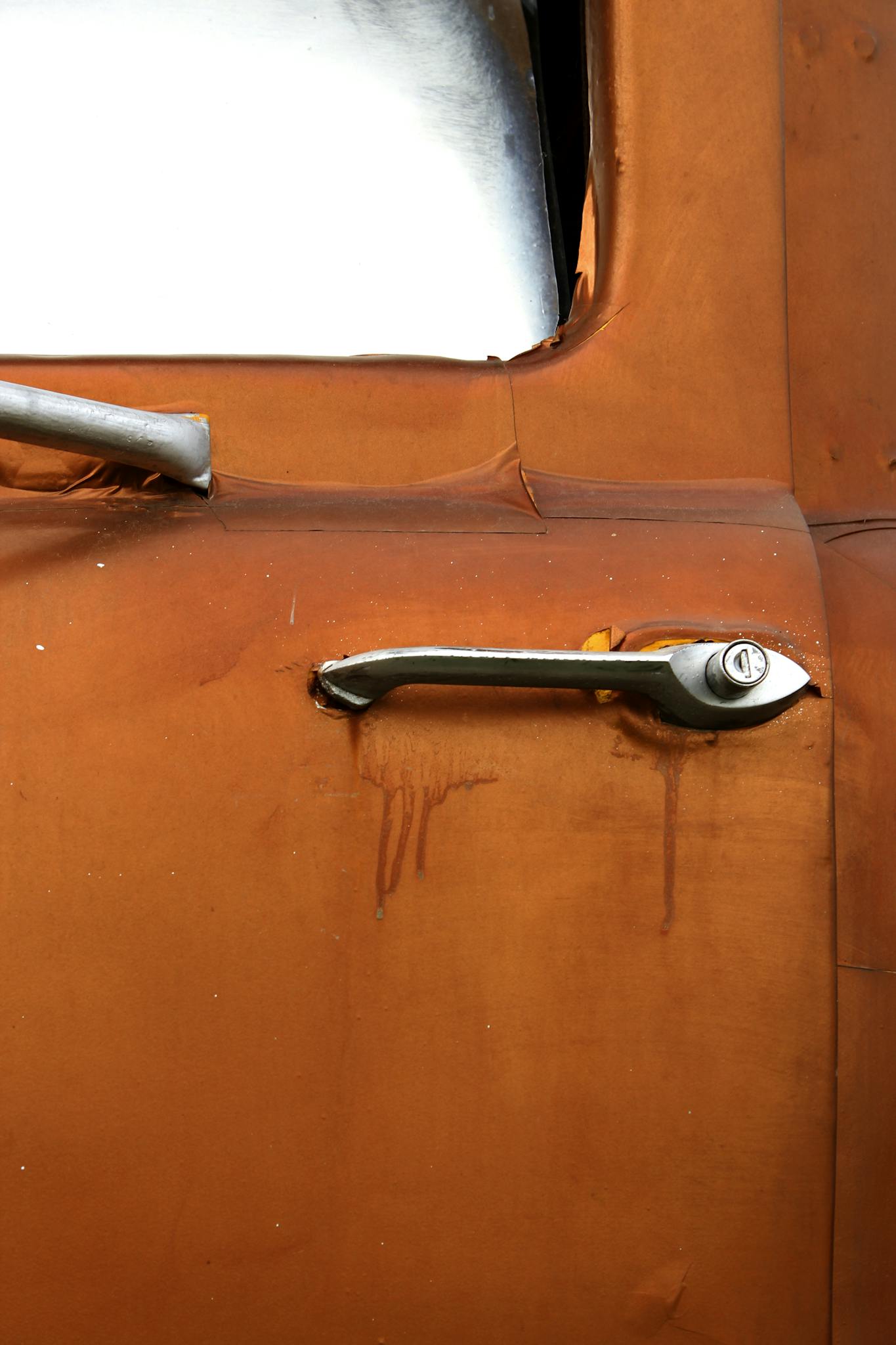 Detailed shot of an old car door handle showing its vintage design and patina.