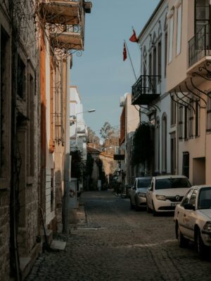 Explore a picturesque cobblestone alley in a quaint European town featuring historic architecture and parked cars.